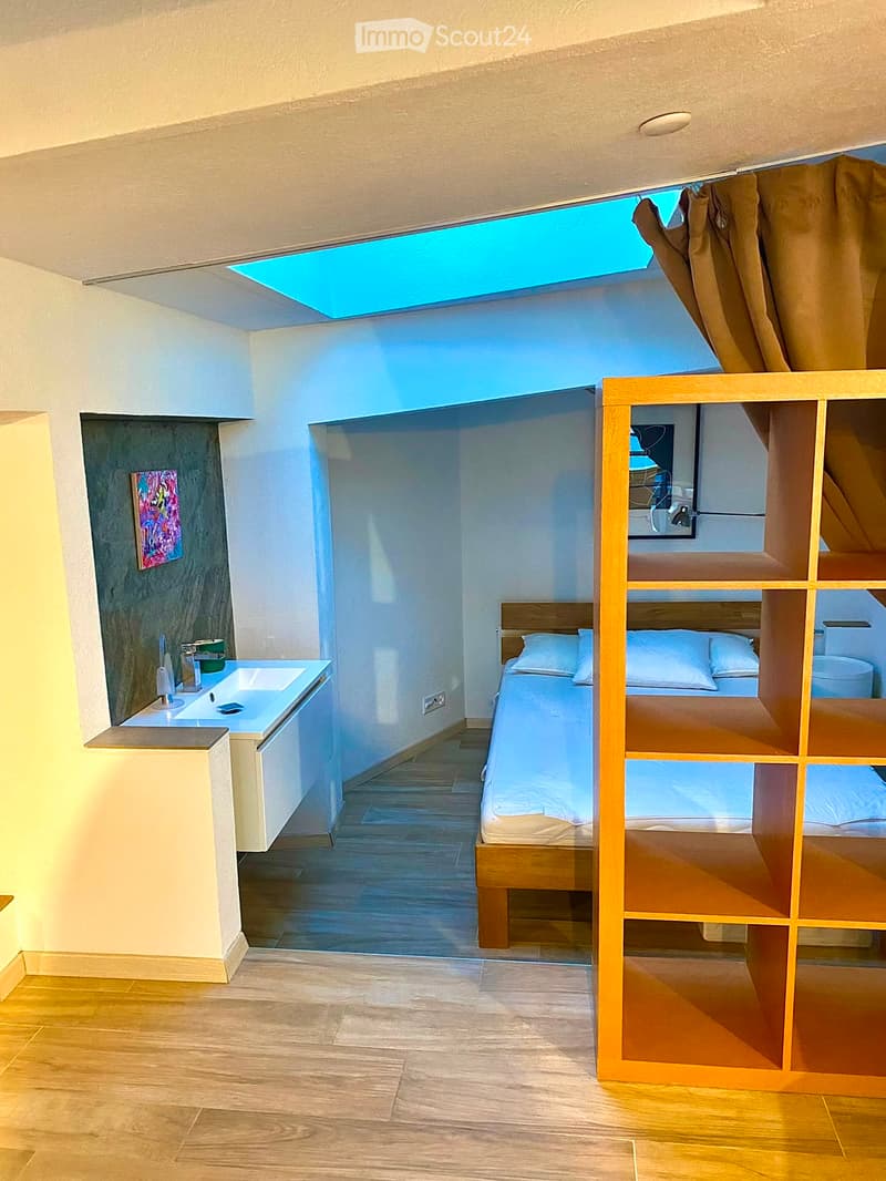 Compact bedroom with a bunk bed, a small sink area, and a skylight window providing natural light. The room features wooden flooring and modern decor.