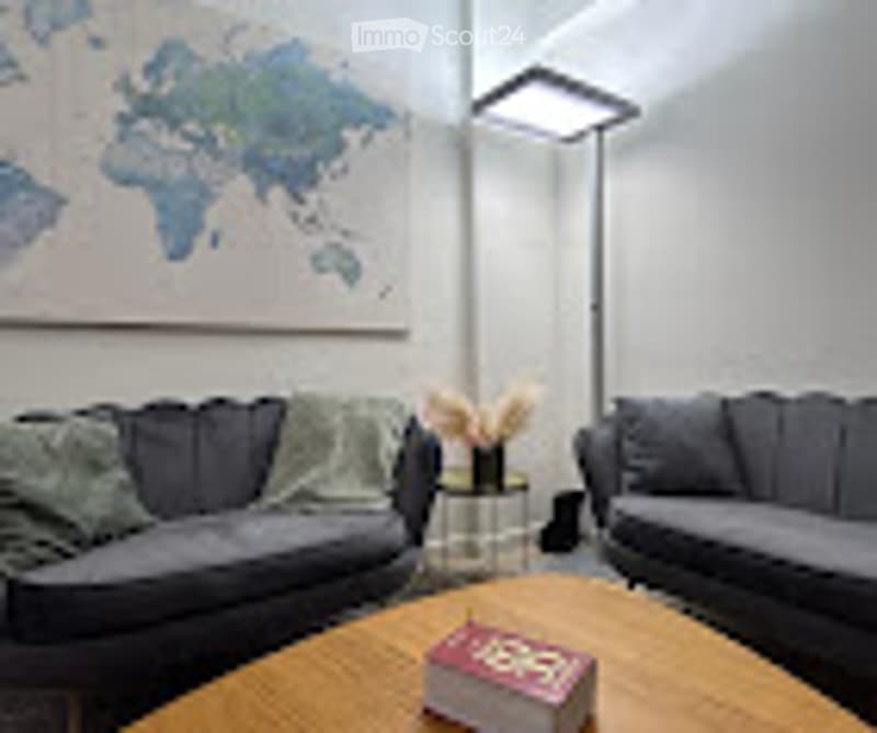 Modern living room with grey sofa, coffee table, world map on wall, side table, and lamp.
