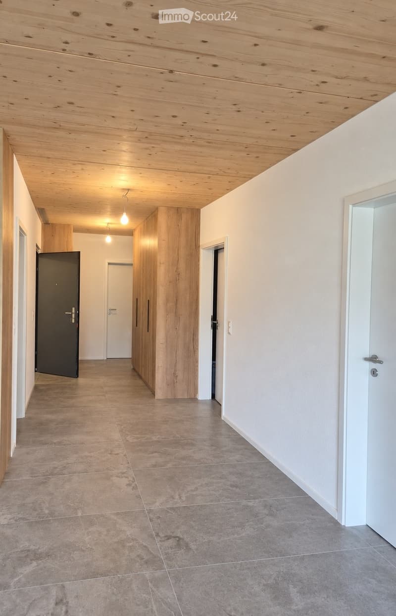 Empty hallway with wooden ceiling, tiled floor, white walls, and several doors leading to other rooms.