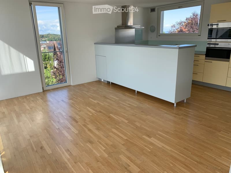 Modern kitchen with light-colored cabinets, a central island, and wooden flooring. Features include a built-in oven and a range hood.