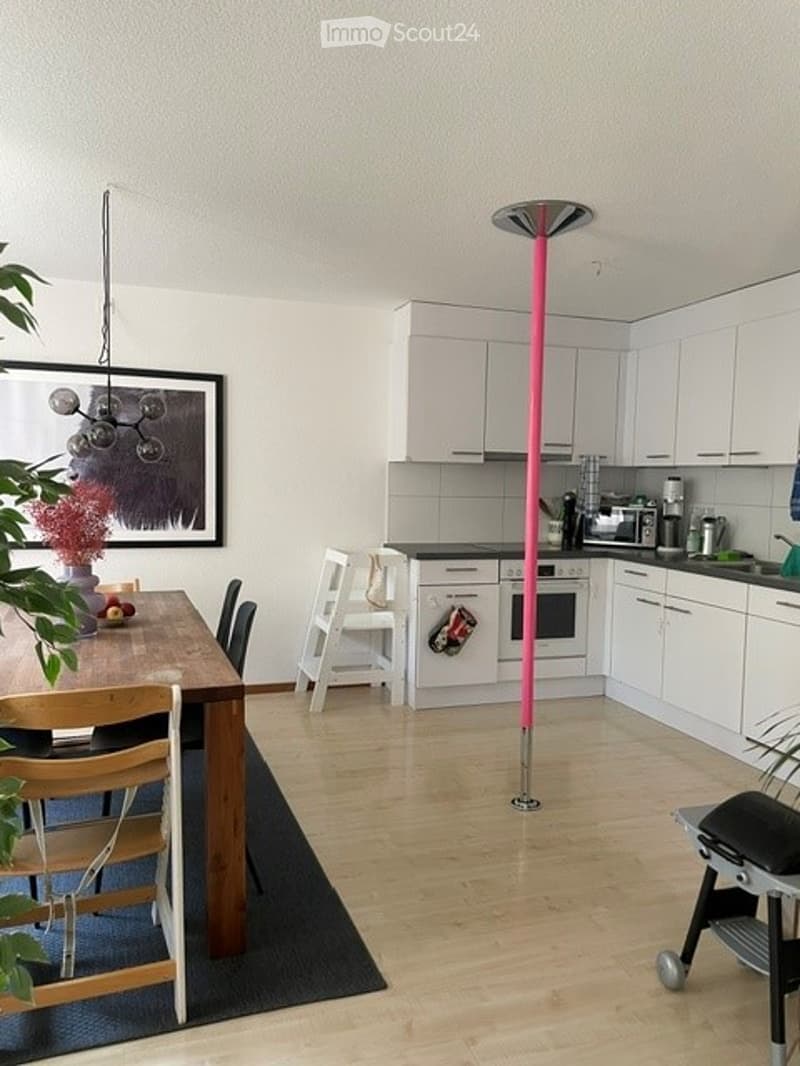 Open-plan kitchen and dining area with white cabinets, a wooden dining table, and modern appliances.