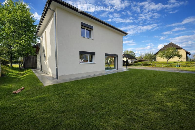 Single-story house with white exterior, large windows, and a well-maintained lawn in front.