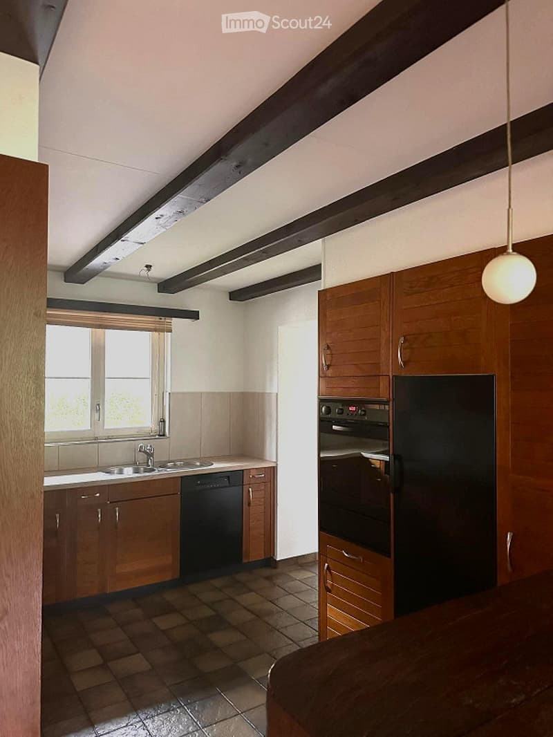 Modern kitchen with wooden cabinets, stainless steel appliances, and a tiled floor. Features a sink, dishwasher, refrigerator, and oven.
