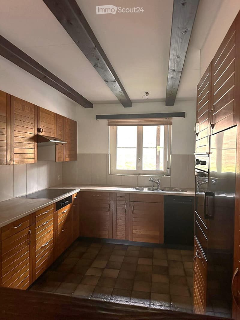 Bright kitchen with wooden cabinets, stainless steel appliances, and a large window letting in natural light.