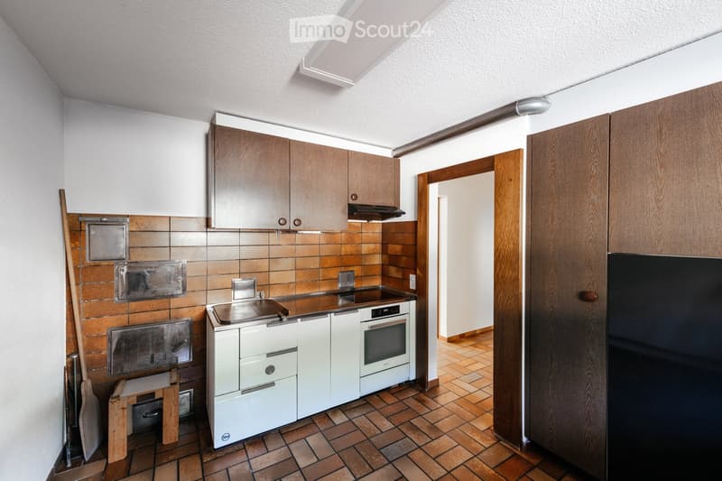 Modern kitchen with wooden cabinets, stainless steel appliances, and tiled backsplash. Features a sink, stove, oven, and refrigerator.