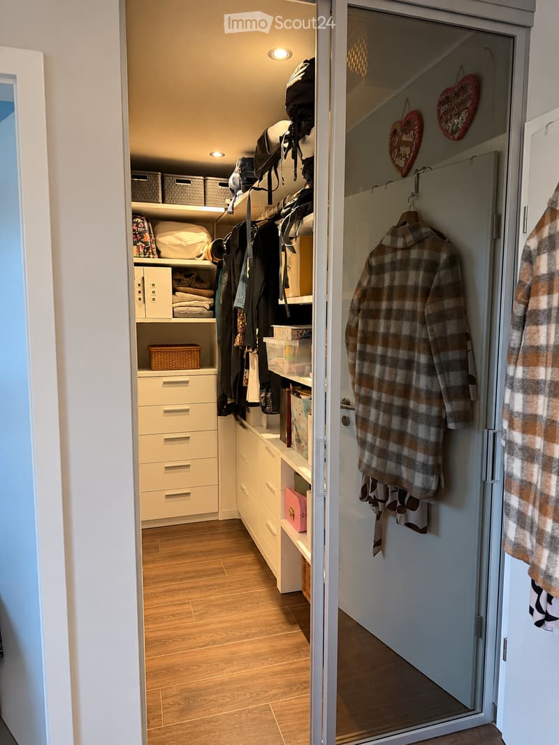 Well-organized hallway with built-in storage units, wooden flooring, and neatly arranged clothing and accessories.