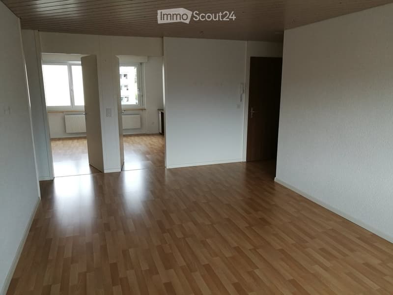 Empty room with wooden flooring, white walls, and large windows allowing natural light. No furniture or equipment is present.