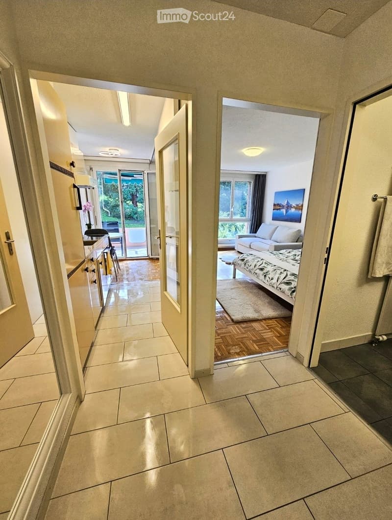 Open layout leading to kitchen, couch, bedroom, windows