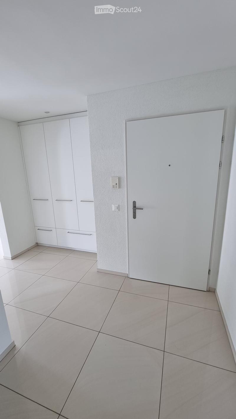 Empty room with white walls, tiled floor, white cabinetry, and a closed door.