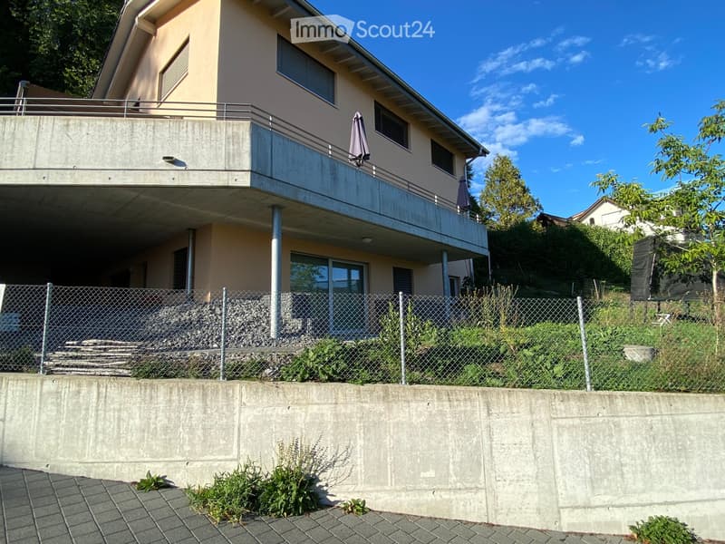 Two-story house with a balcony, modern design, and a fenced yard.