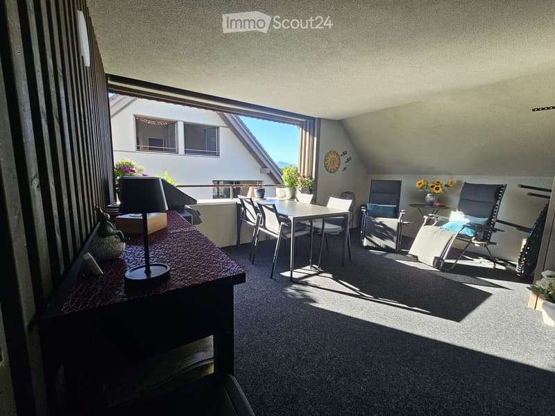 Balcony with a small table, chairs, and a lamp, featuring a view of the surrounding area.