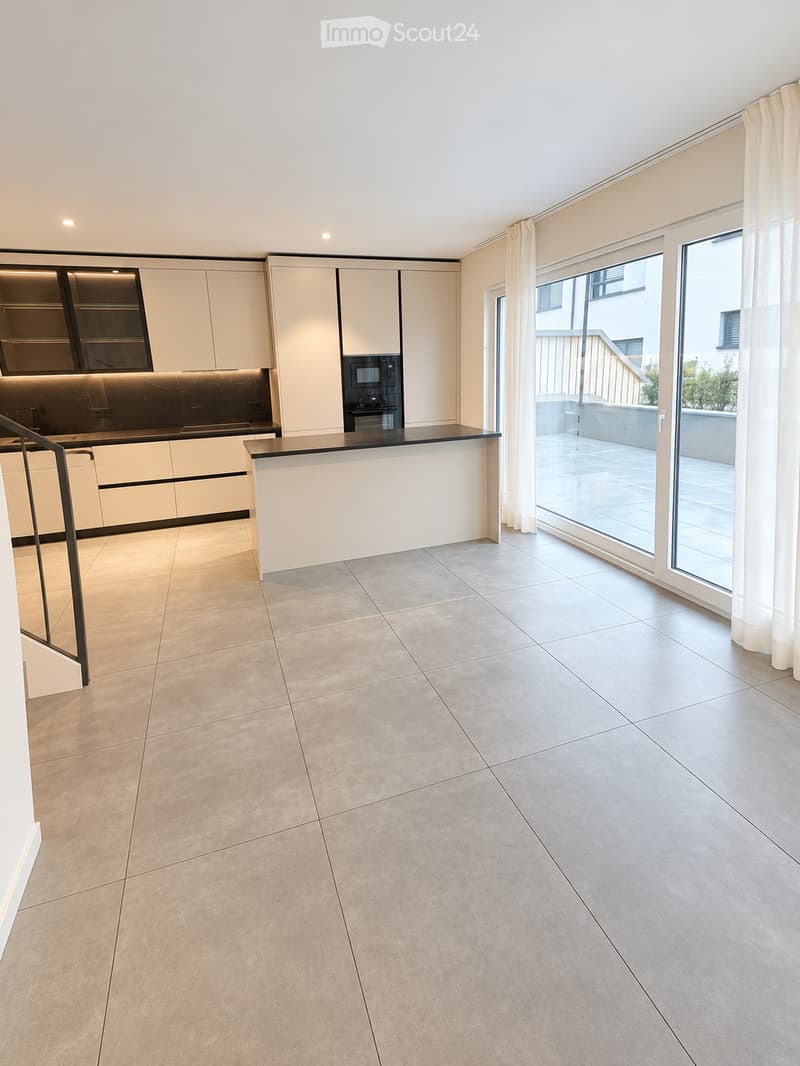 Modern kitchen with white cabinetry, black countertop, built-in oven and microwave, large windows with white curtains, and a central island.