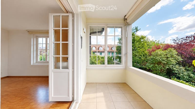Empty room with wooden flooring, large windows, and a view of greenery outside. No furniture or equipment present.