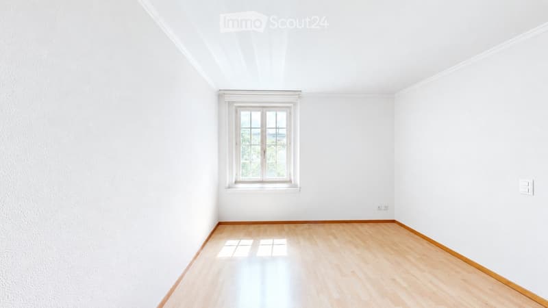 Empty room with white walls, wooden floor, and a single window with white frame. No furniture or equipment present.