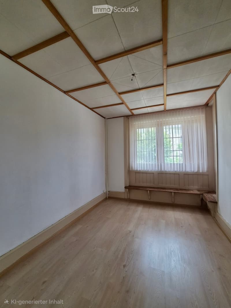Empty room with wooden flooring, white walls, and a wooden bench along one wall. The ceiling features exposed wooden beams and a skylight. Natural light filters through sheer curtains on the windows.