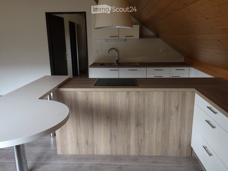 Modern kitchen with a wooden island, white cabinets, stainless steel sink, and a pendant light fixture.