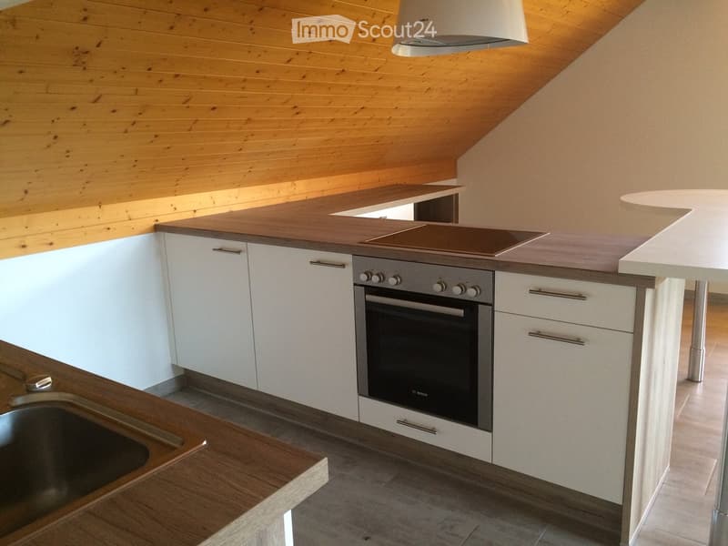 Modern kitchen with white cabinets, wooden countertops, stainless steel oven, and island with sink.
