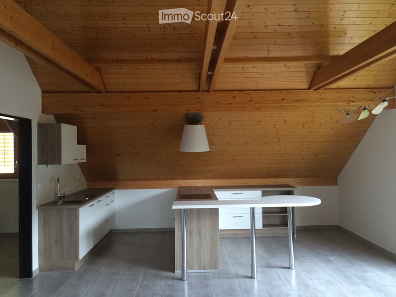 Modern kitchen with wooden ceiling beams, white cabinets, a central island, and a round table with metal legs.