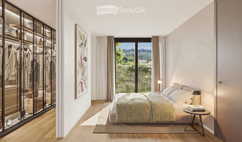 Modern bedroom with a large bed, nightstand, small table with books, floor lamp, and a large wardrobe with mirrored doors. Large windows offer a scenic view of greenery.