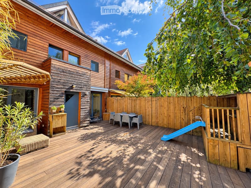 Wooden deck area with a table, chairs, a small slide, potted plants, and a wooden fence surrounding the space.