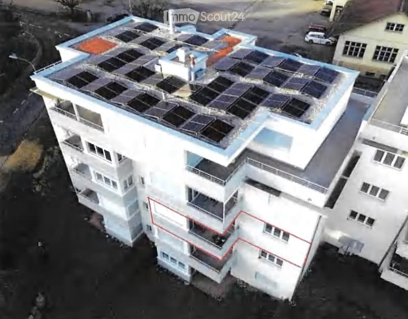 A multi-story building with solar panels on the roof, multiple balconies, and a modern design.