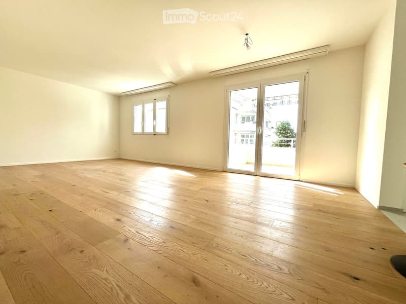 Empty room with wooden flooring, large sliding glass doors, and a window on the left side.