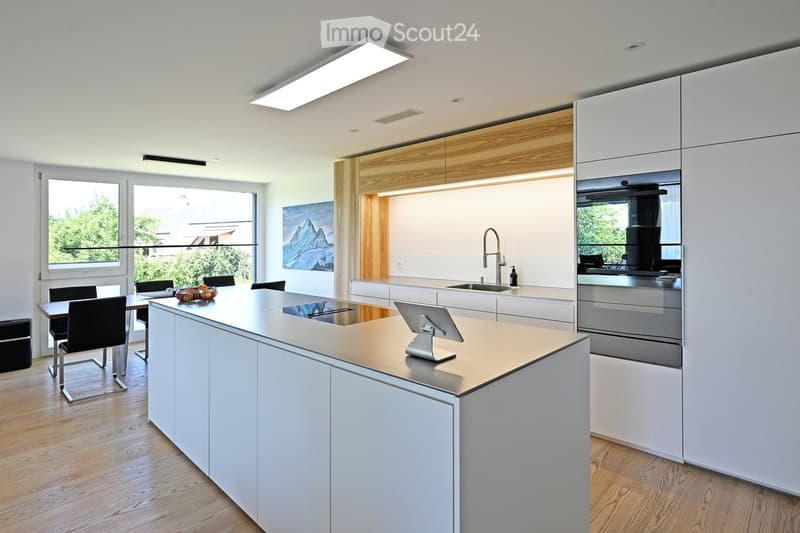 modern kitchen with an island, white cupboards, wooden floors, large windows with balcony
