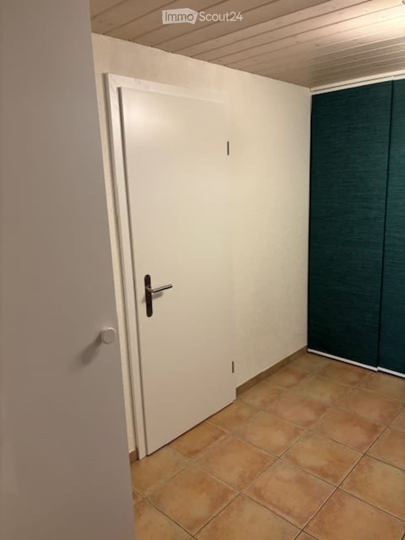Empty room with tiled floor, white walls, and a closed white door.
