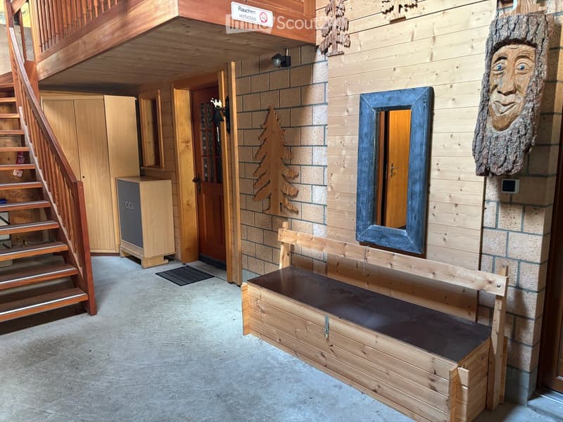 Wooden hallway with a bench, mirror, and cabinet, featuring a staircase leading upwards and a door to another room.
