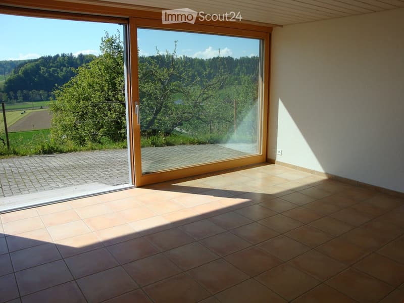 Empty room with tiled floor and large sliding glass door leading to a patio and scenic outdoor view.