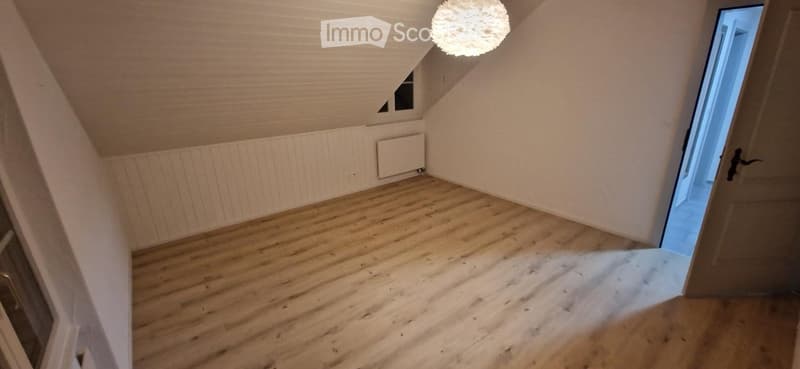 Empty attic room with wooden flooring, white walls, and a skylight window. No furniture or equipment present.