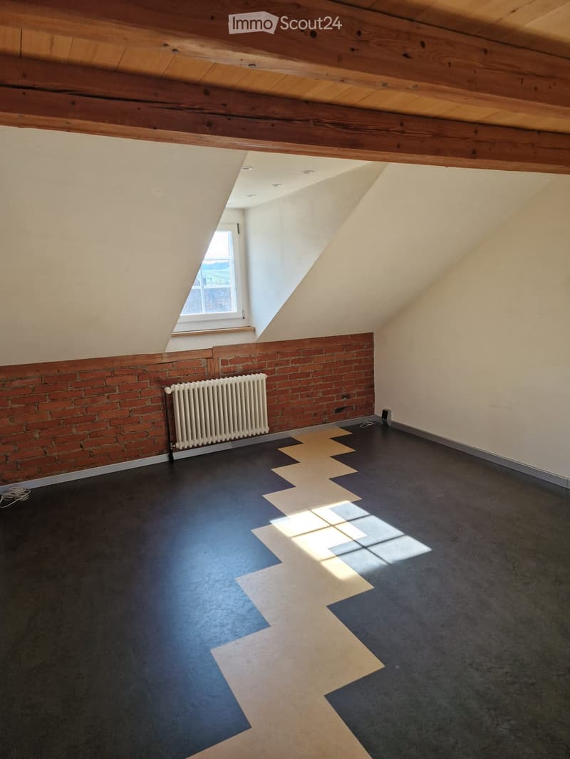 empty room, brick wall, radiator, sloped ceiling, attic window, black and white floor