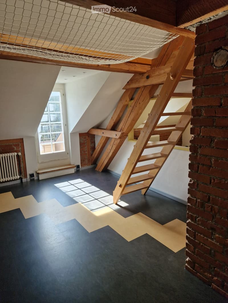 loft-style room with wooden beams, brick walls, wooden ladder, large window
