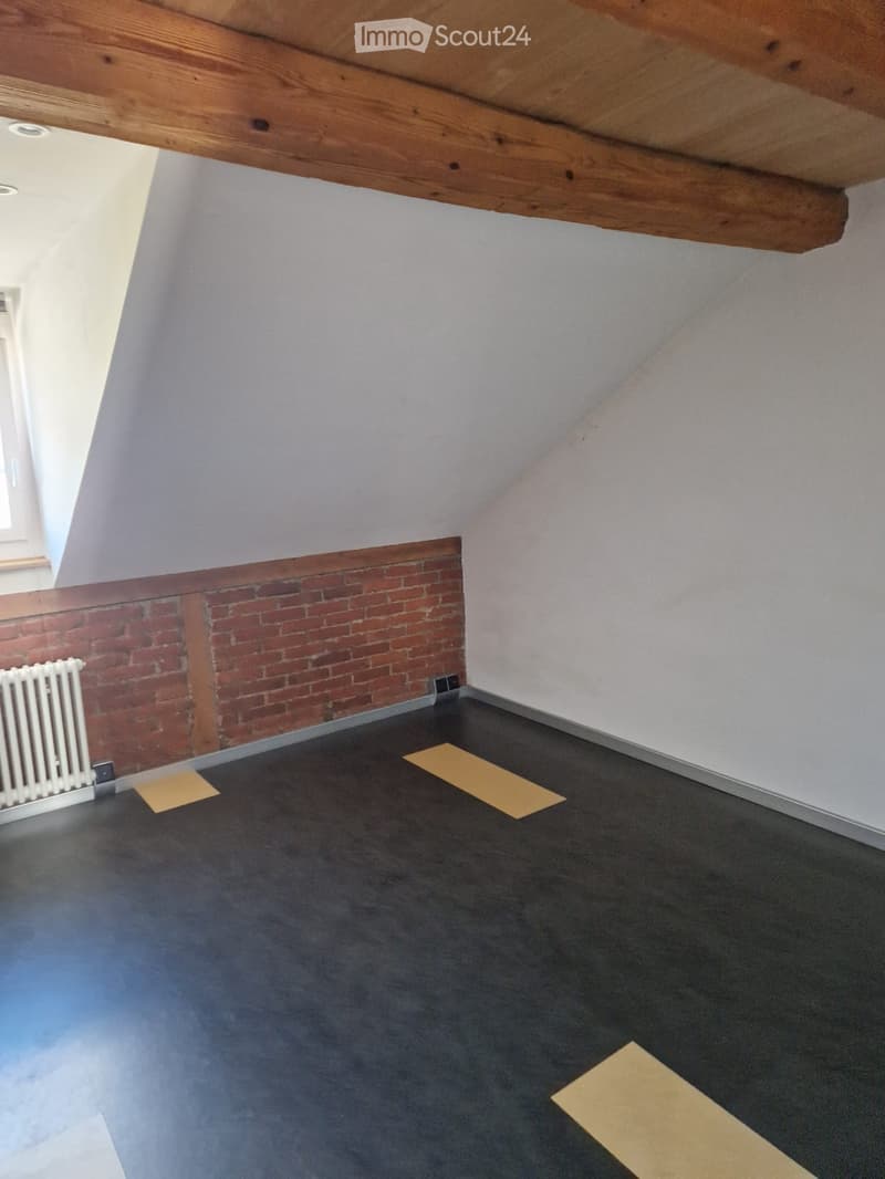 empty room, wooden ceiling, brick wall, black floor, white wall, small window, white radiator