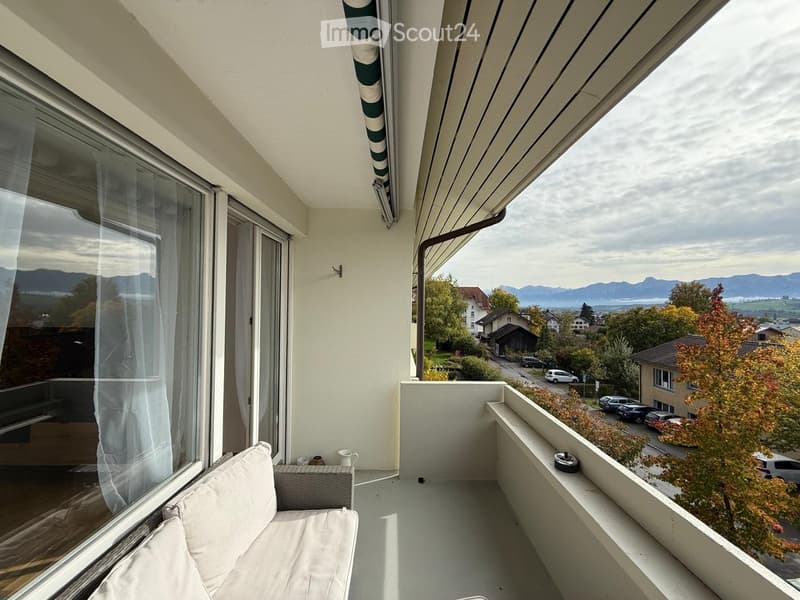 Balcony with a sofa, small table, and scenic mountain view.