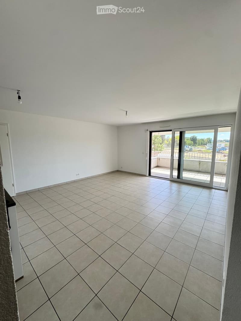 Empty room with tiled floor, white walls, and large sliding glass doors leading to a balcony.