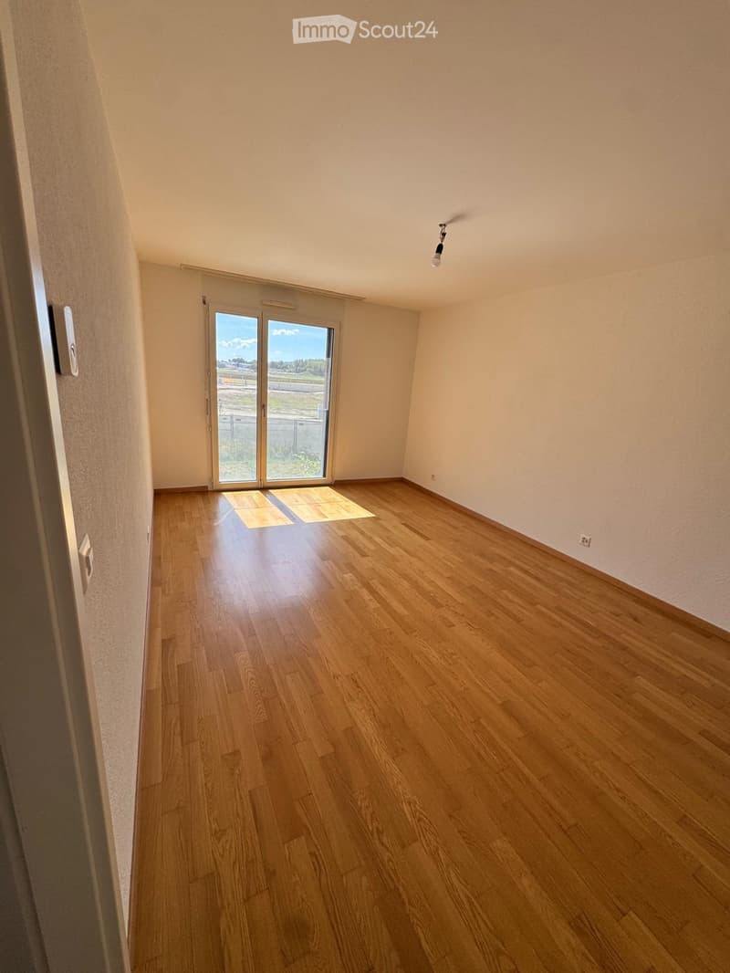 Empty room with wooden flooring, large sliding glass door, and natural light. No furniture or equipment present.