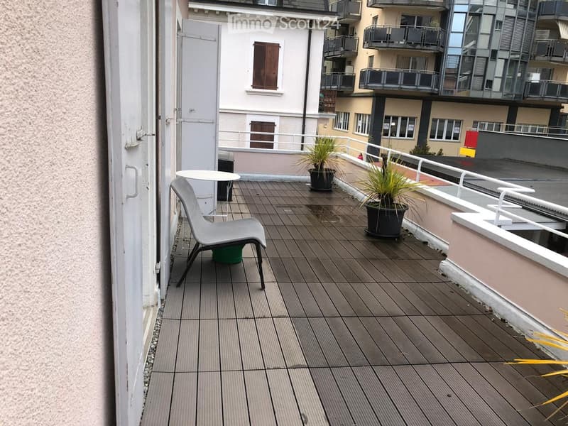Balcony with wooden decking, a single chair, a small table, and potted plants.