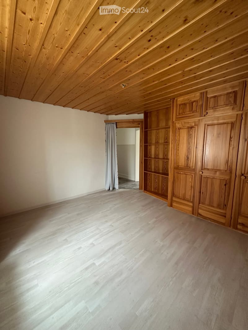 Unfurnished Room. Empty room with wooden ceiling, white walls, and wooden floor. There is a large wooden wardrobe on the right side.