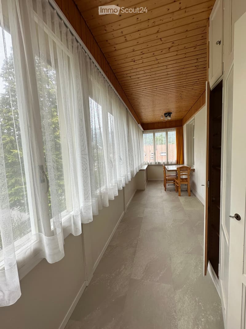 Unfurnished Room. Empty room with white walls, wooden ceiling, white curtains, and tiled floor. There is a small table and chairs in the corner.