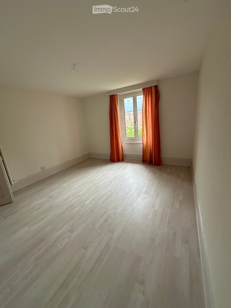 Unfurnished Room. Empty room with white walls, wooden floor, and a window with orange curtains.