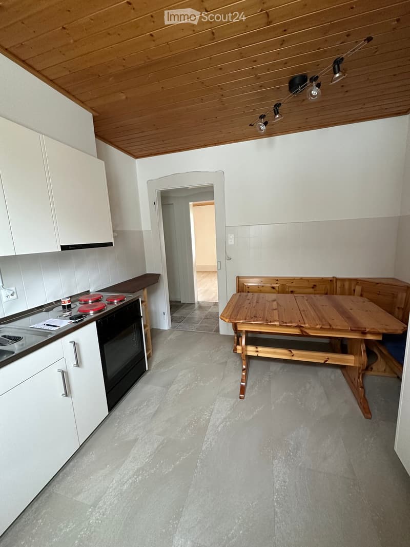 Kitchen. Modern kitchen with white cabinets, wooden table, black oven, and red burners.