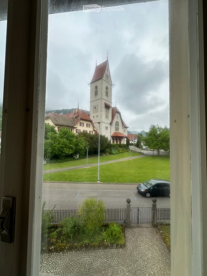 Unfurnished Room. View from a window showing a church, a car parked in a parking lot, and a grassy area with a pathway.