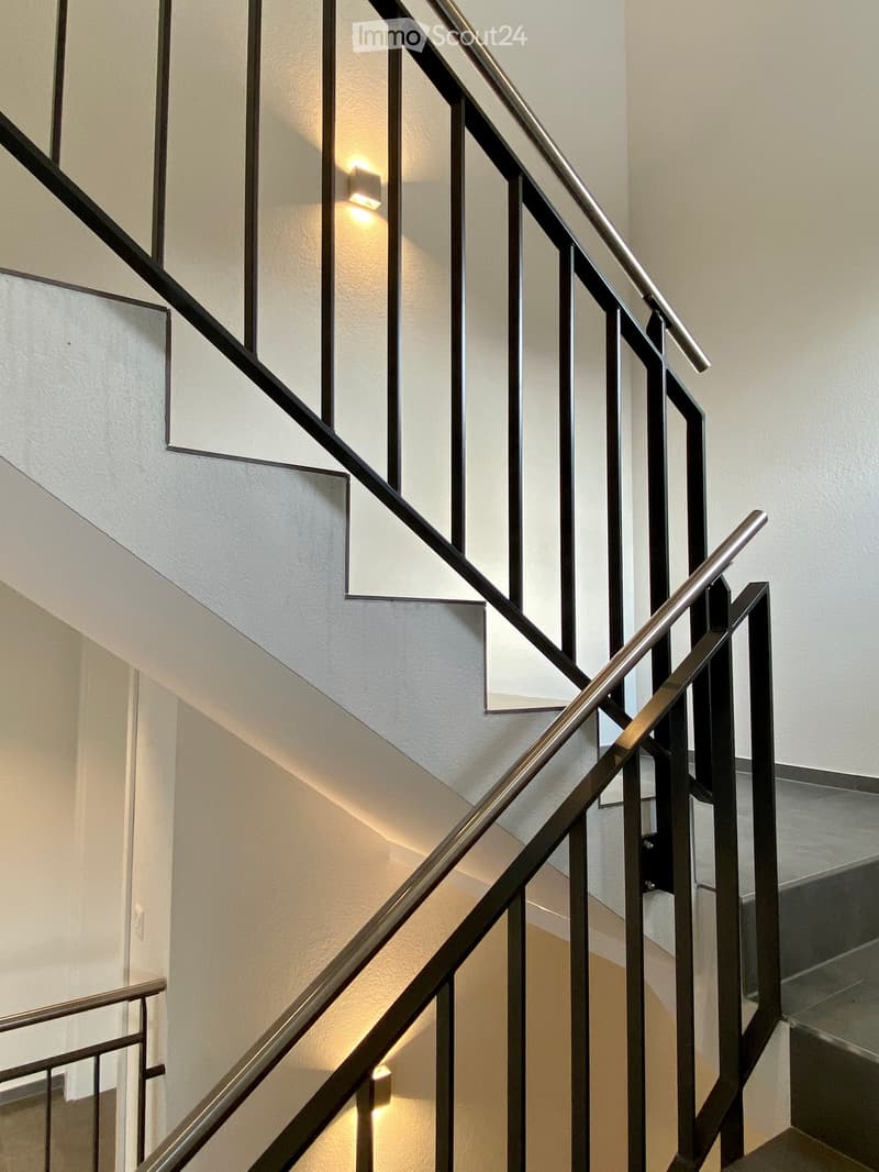 Modern staircase with sleek metal railings and warm ambient lighting, featuring a clean and contemporary design.