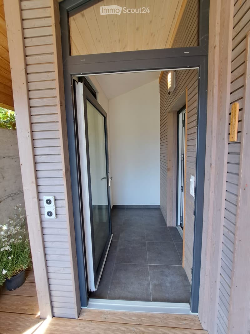 Modern hallway with wooden paneling, dark tiled floor, and a glass door leading to another room.