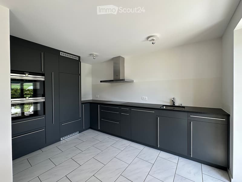 Modern kitchen with dark grey cabinets, stainless steel appliances, marble tile flooring, and a central island with a sink and faucet.