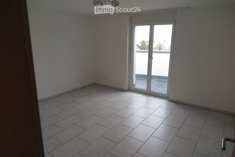 Empty room with tiled floor, white walls, and large sliding glass door leading to a balcony.