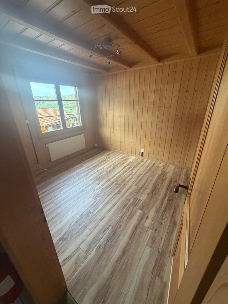 Empty room with wooden walls, wooden floor, large windows, and a skylight. No furniture or equipment visible.