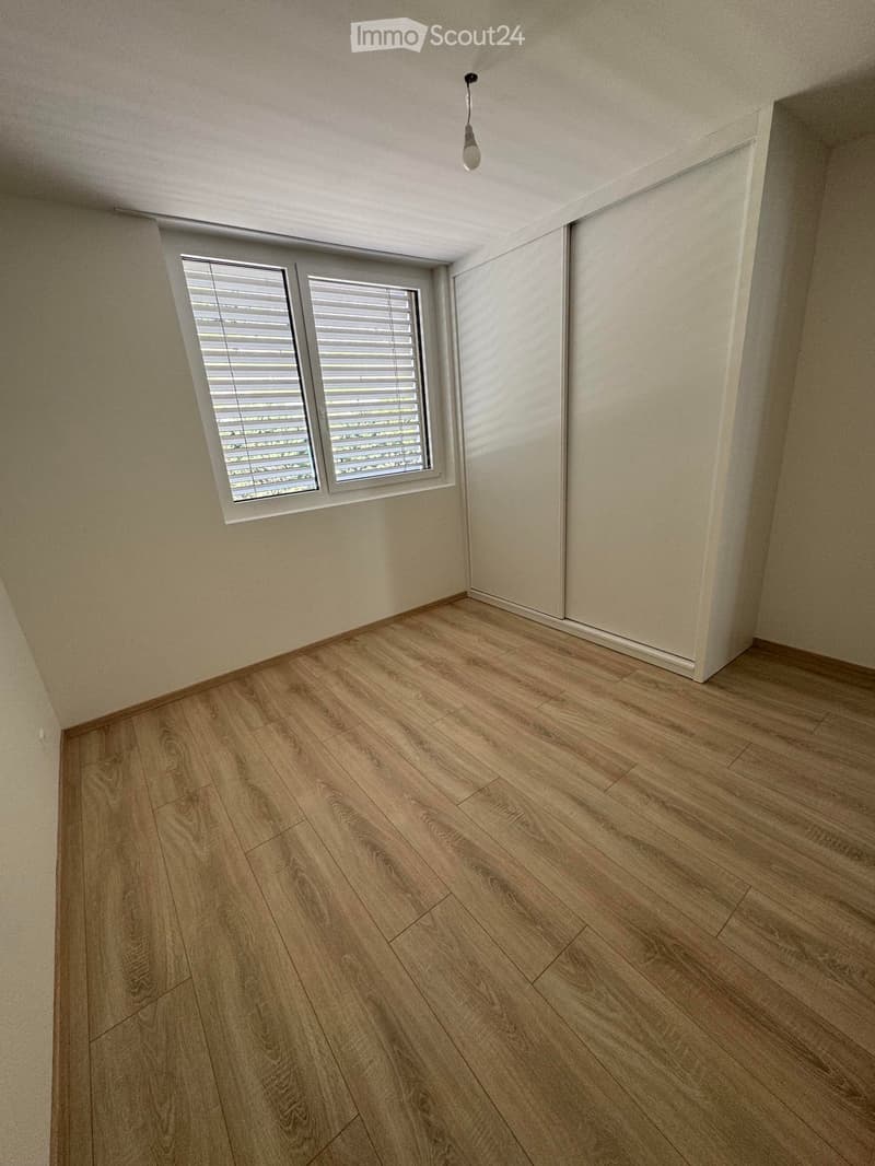 Empty room with light wooden flooring, white walls, and a window with blinds. No furniture or equipment is present.