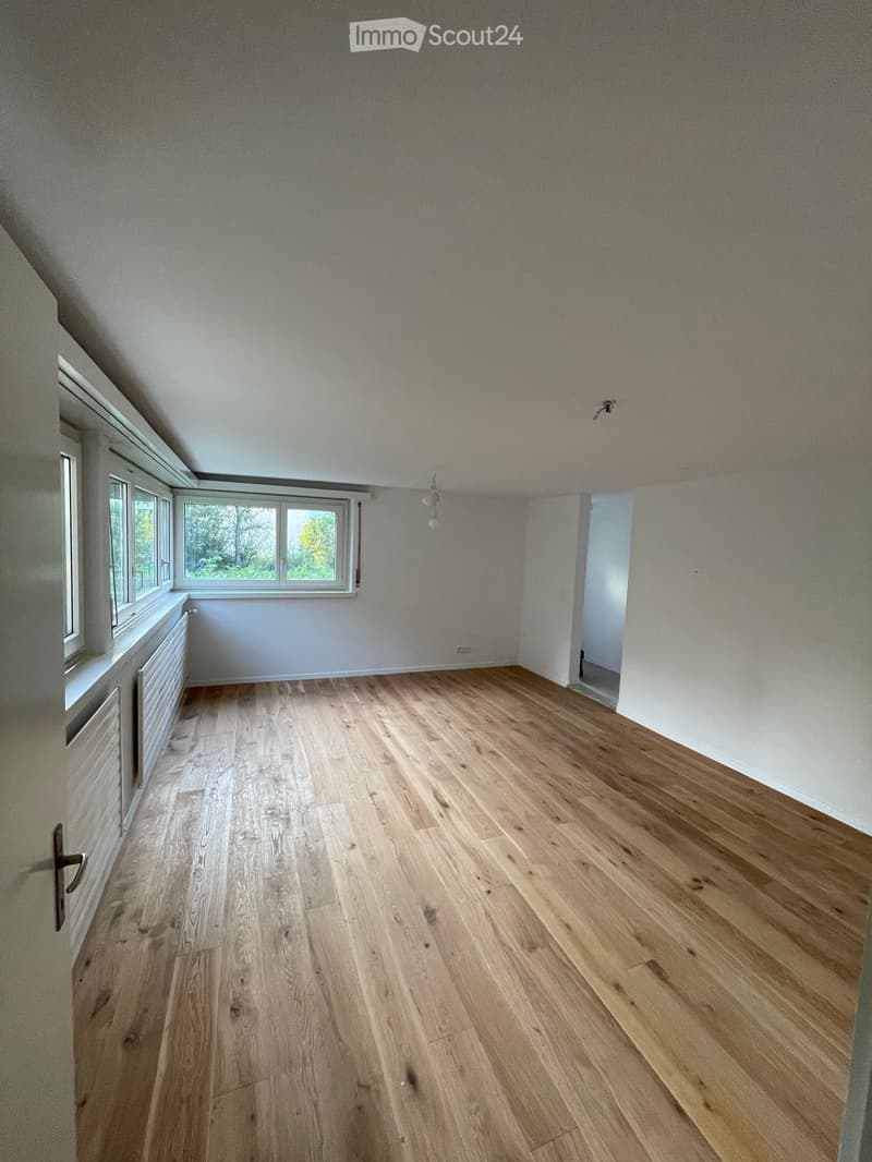 Empty room with wooden flooring, white walls, and large windows letting in natural light. No furniture or equipment present.